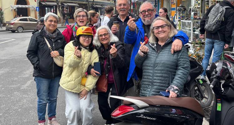 Groupe de touristes posant dans une rue avec des motos et des magasins locaux.