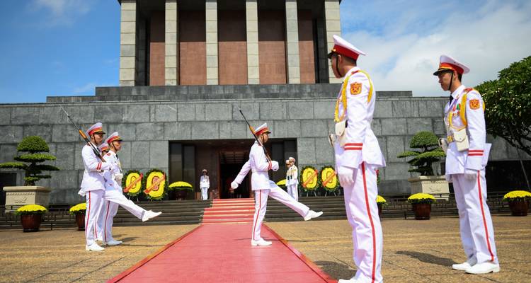 Des soldats en uniforme exécutant une cérémonie officielle devant un mausolée.