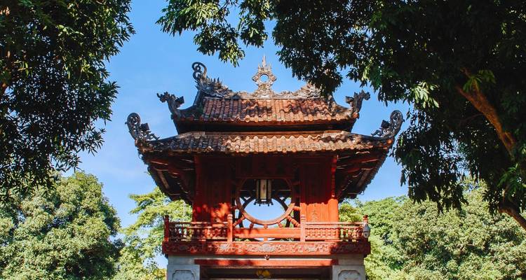Porte de temple vietnamien traditionnel entourée d'arbres.