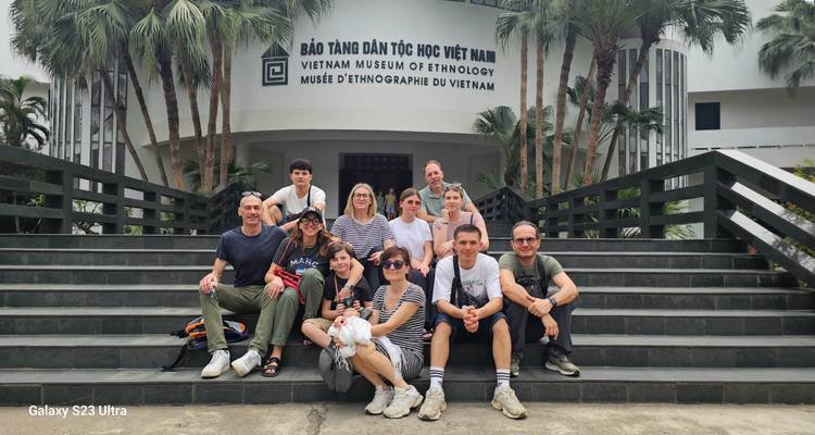 Groupe de touristes posant sur les escaliers du Musée d'ethnologie du Vietnam avec un filigrane.