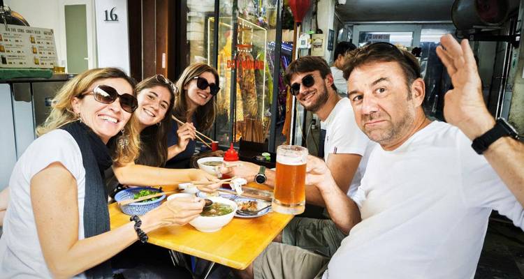 Groupe d'amis prenant un repas et des boissons dans un café en plein air.