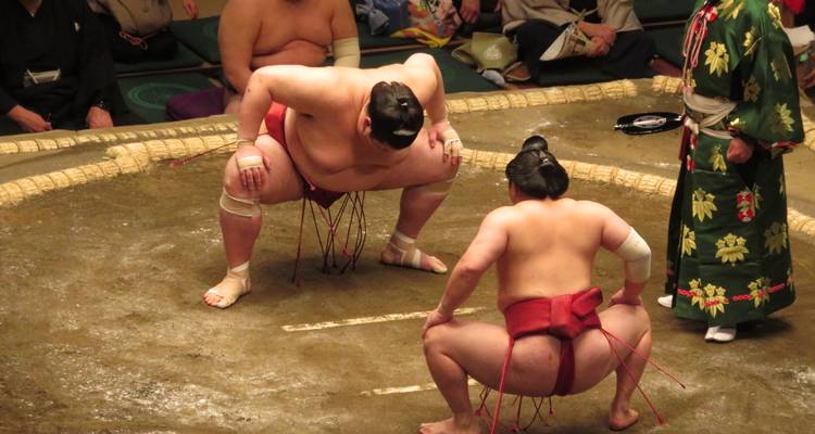 Deux lutteurs de sumo se préparant à lutter dans un ring.