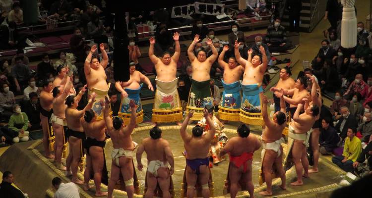 Groupe de lutteurs de sumo debout en cercle dans une arène.