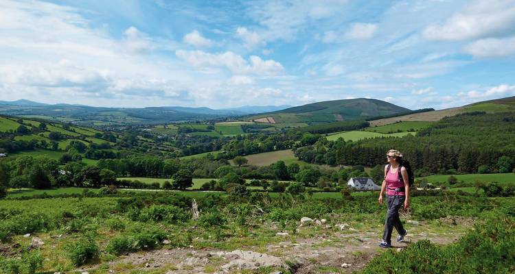 Excursionista caminando por un valle pintoresco con colinas verdes.
