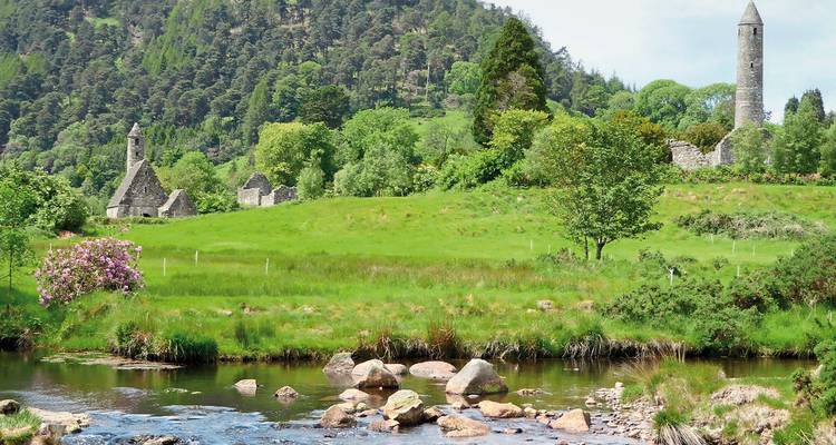 Campos verdes con sitio monástico antiguo y torre redonda.