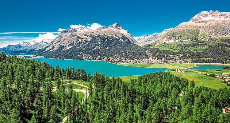 Bergige Landschaft mit einem blauen See und grünen Wäldern.