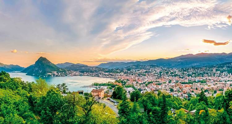 Panoramablick auf eine Stadt am See mit bergiger Kulisse.