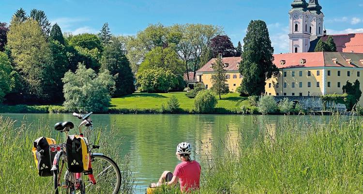 Une personne profitant d'une vue paisible au bord d'une rivière avec un vélo à proximité.