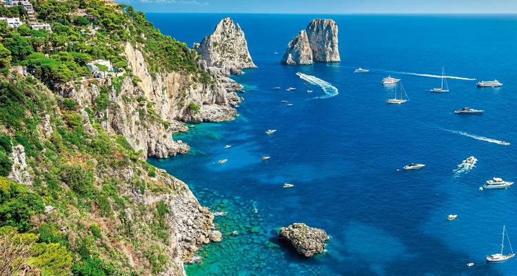 Vue depuis la falaise avec des bateaux et un océan bleu limpide.