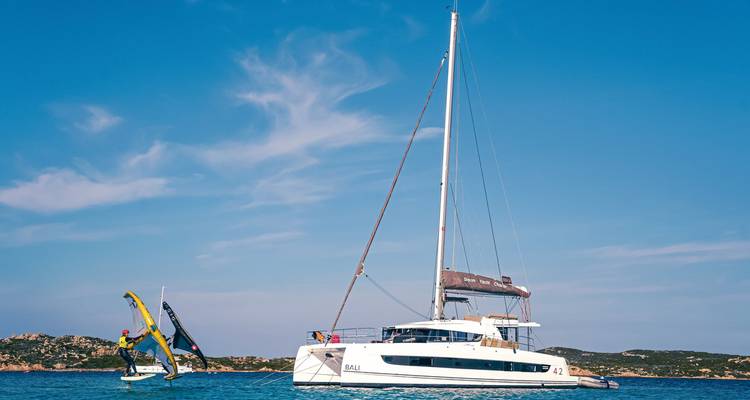 Voilier avec une personne sur une planche à voile à côté.