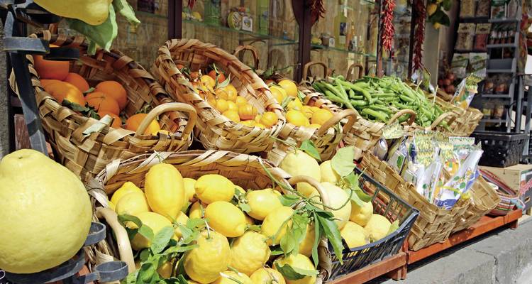 Étalage de marché avec des paniers de citrons et d'autres fruits.