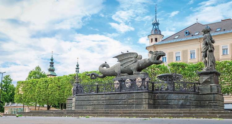 Drakenfontein op een Europees stadsplein tegen een blauwe hemel.