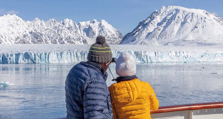 Deux personnes en vêtements d'hiver regardant un glacier depuis un bateau de croisière.