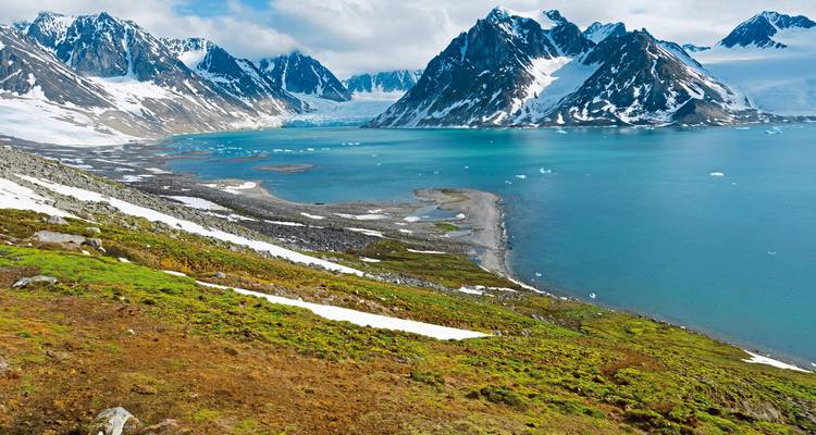 Paysage arctique avec une baie entourée de montagnes enneigées.