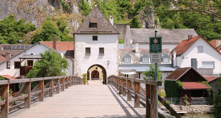 Een houten brug die leidt naar een historische poort in een schilderachtig stadje.