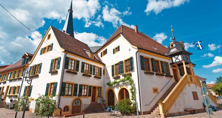 Bâtiment traditionnel allemand avec toits pentus et fenêtres décoratives, ensoleillé.