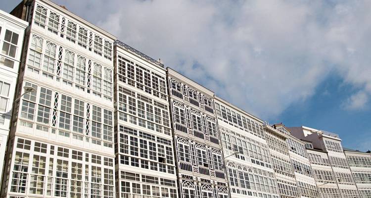 Historische Gebäude mit Glasfronten vor blauem Himmel.