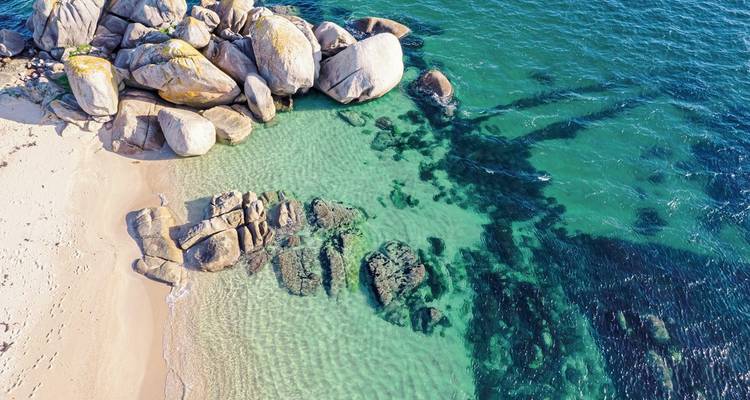 Felsiger Strand mit klarem türkisfarbenem Wasser.