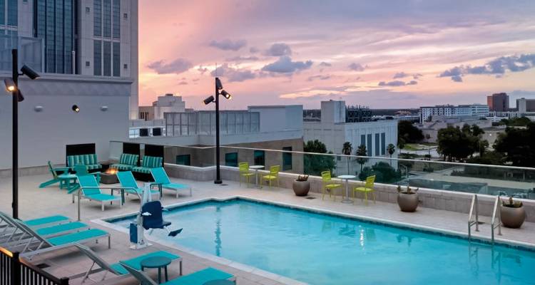 Scène de piscine sur le toit au coucher du soleil, surplombant un paysage urbain.