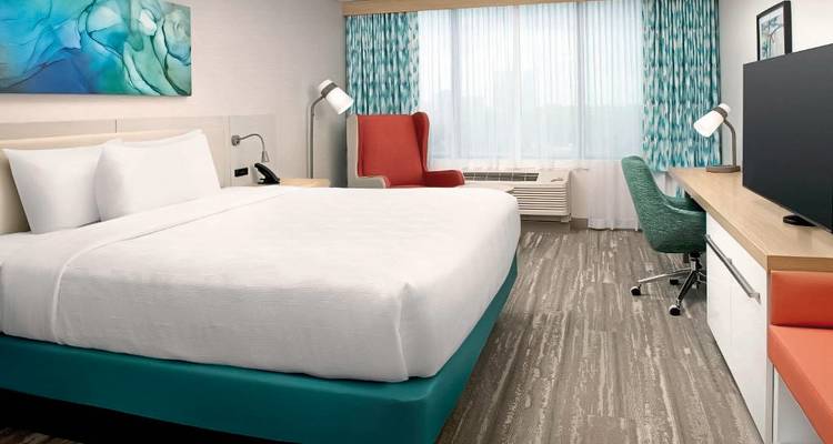 Intérieur de chambre d'hôtel moderne avec un grand lit, un bureau et un coin salon.