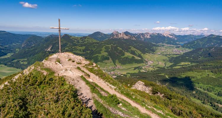 Mountain landscape with a cross and valley below.