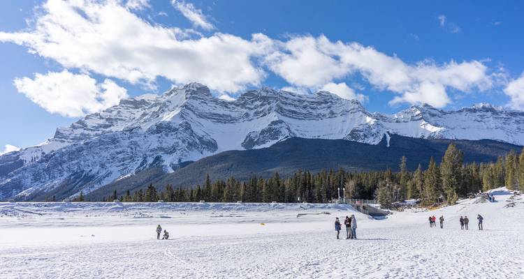 Montagnes enneigées avec quelques touristes qui interagissent sur le lac gelé.