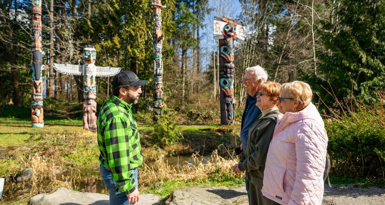 Trois personnes interagissant avec des totems dans un environnement forestier.