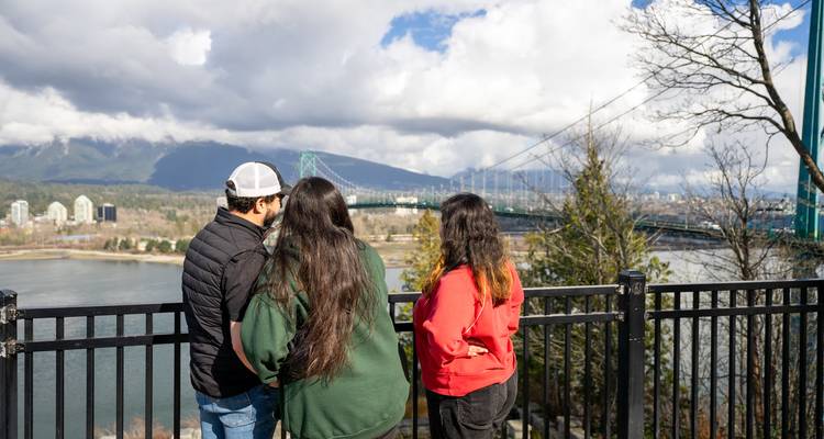 Trois personnes surplombant un paysage de pont et de rivière.