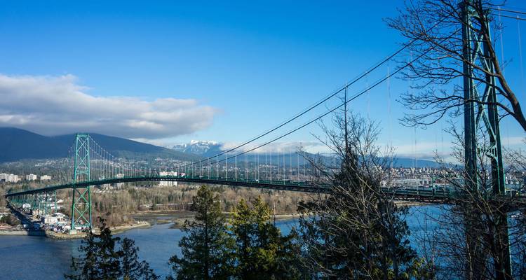 Une vue pittoresque de pont avec la ville et les montagnes en arrière-plan.