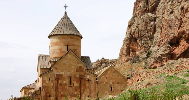 Alte Steinkirche vor einem felsigen Hang.