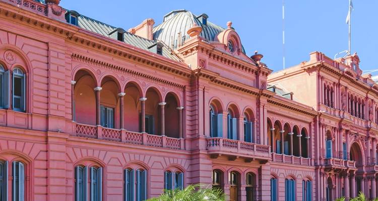 Bâtiment historique avec façade rose et fenêtres cintrées.