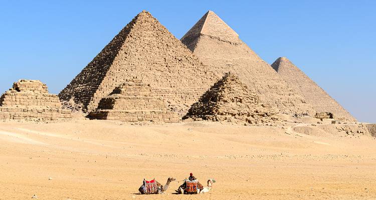 Ikonische Pyramiden von Giza, die sich aus der Wüste erheben, mit Kamelreitern, die sich im Vordergrund ausruhen