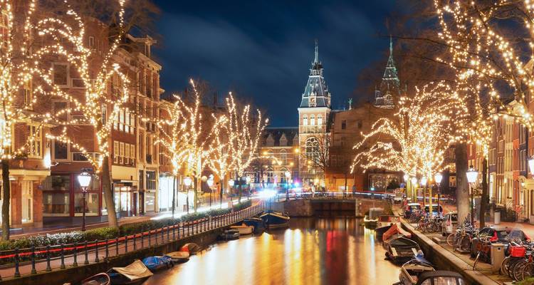 Nachtansicht eines Kanals mit beleuchteten Gebäuden und Bäumen.