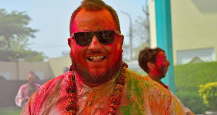 Man bedekt met kleurrijke poeders die een festival viert.