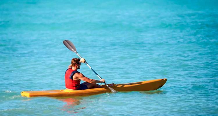 Una persona navegando en kayak en aguas turquesas del océano.