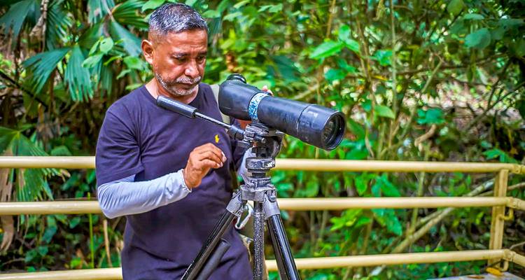 Man met een telescoop in een bosomgeving.