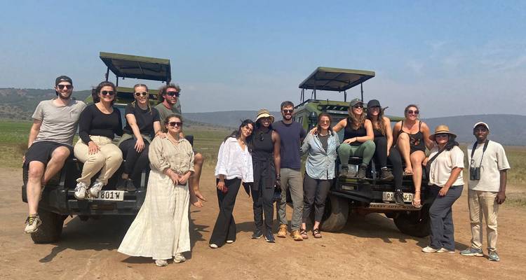 A group of people posing with safari vehicles on a sunny day.