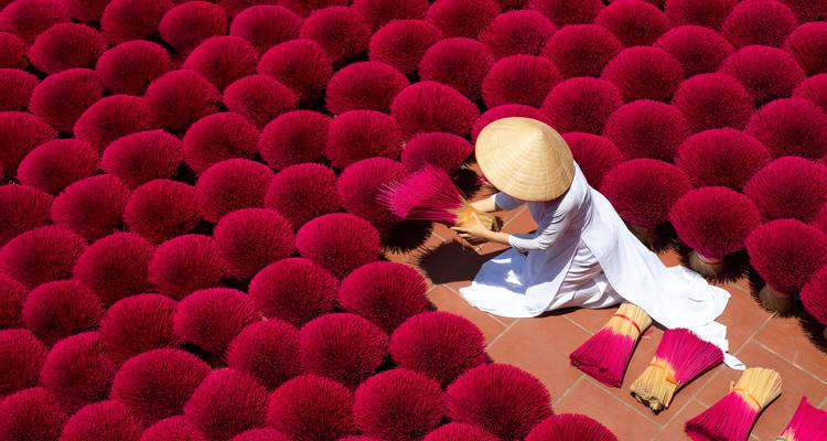 Frau, die rote Räucherstäbchen auf dem Boden anordnet.