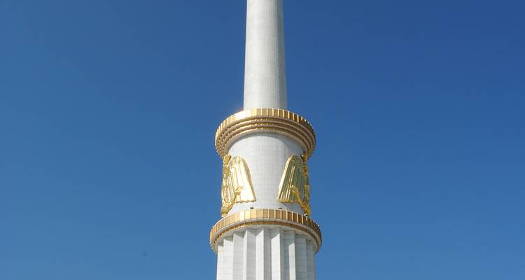 Un monument blanc et élancé avec des ornements dorés contre un ciel bleu.