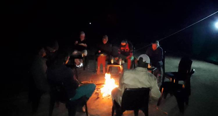Un groupe de personnes assises autour d'un feu de camp la nuit.