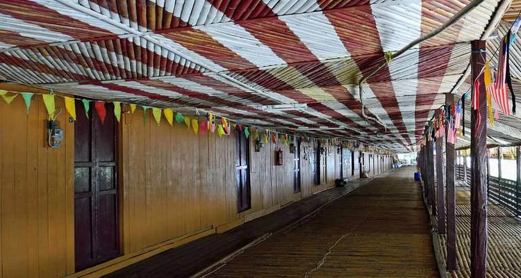 Largo corredor de madera de una casa comunal tradicional de Borneo decorado con banderas colgantes.