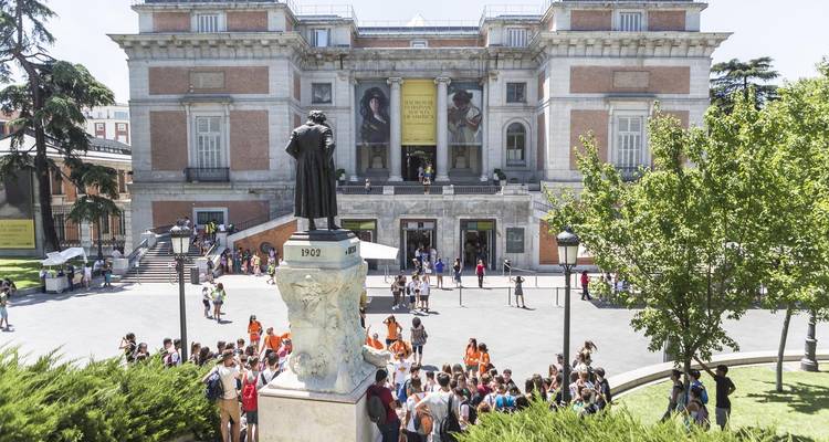 Vue de face d'un bâtiment historique avec une zone d'entrée bondée.