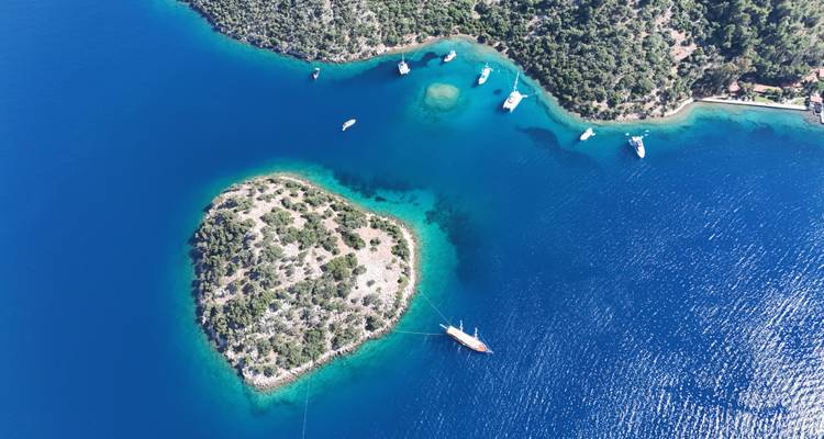 Vue aérienne d'une petite île entourée d'une mer bleue.