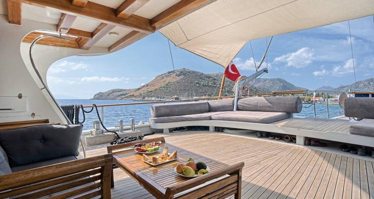 Ruim dek van een zeiljaht met Turkse vlag, met uitzicht op een schilderachtige baai.