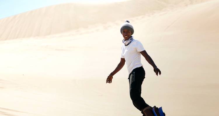 Person sliding down a sand dune.