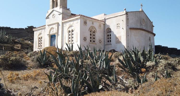 A small Greek church on a hilltop surrounded by aloe plants.