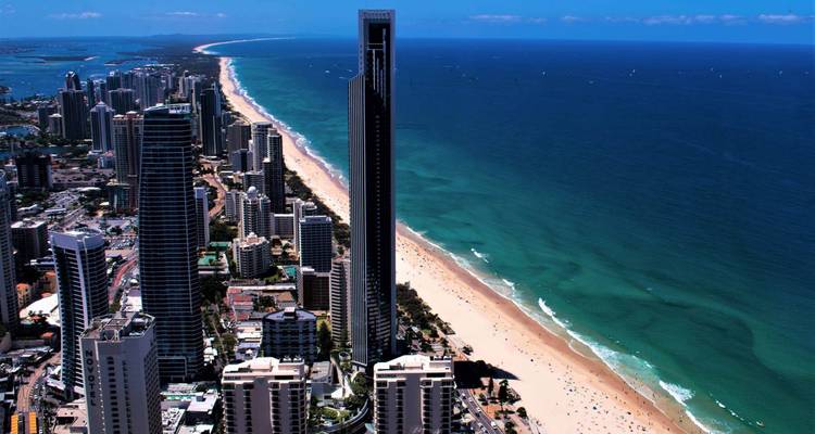 Aerial view of a coastal city with skyscrapers lining a sandy beach.