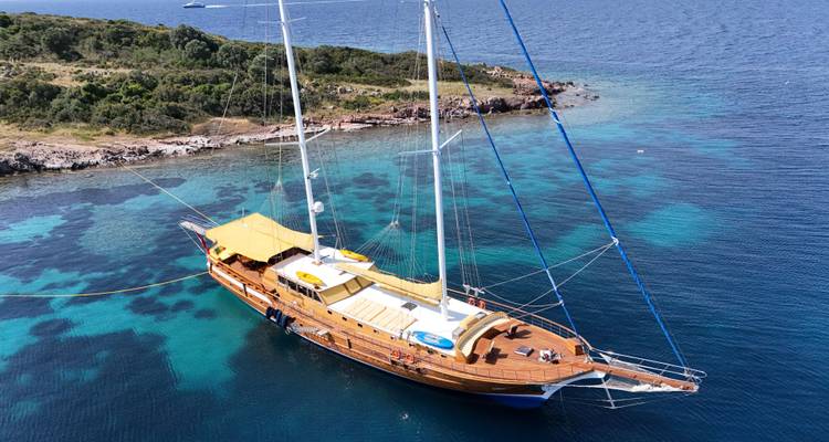Vue aérienne d'un yacht à voile luxueux dans une eau cristalline.