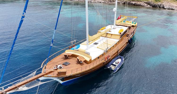 Yacht à voile blanc ancré dans une baie pittoresque aux eaux claires.