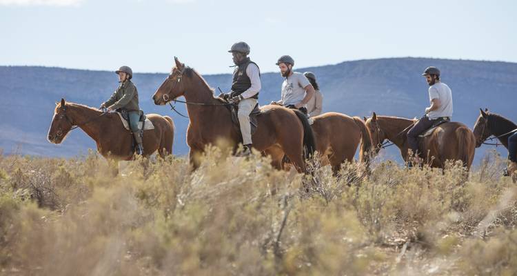 Group of horse riders traversing a mountainous area.